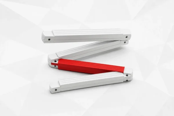 Un metro plegable de carpintero, facetado y blanco, doblado en zigzag con uno de los tramos rojo